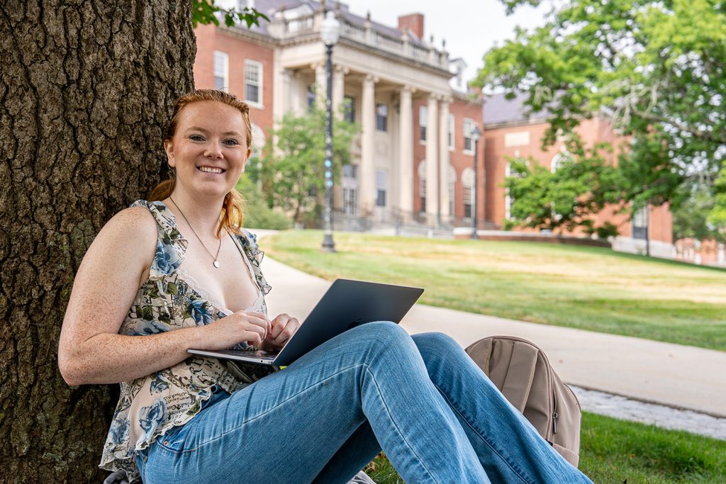 student sitting outside working on a laptop