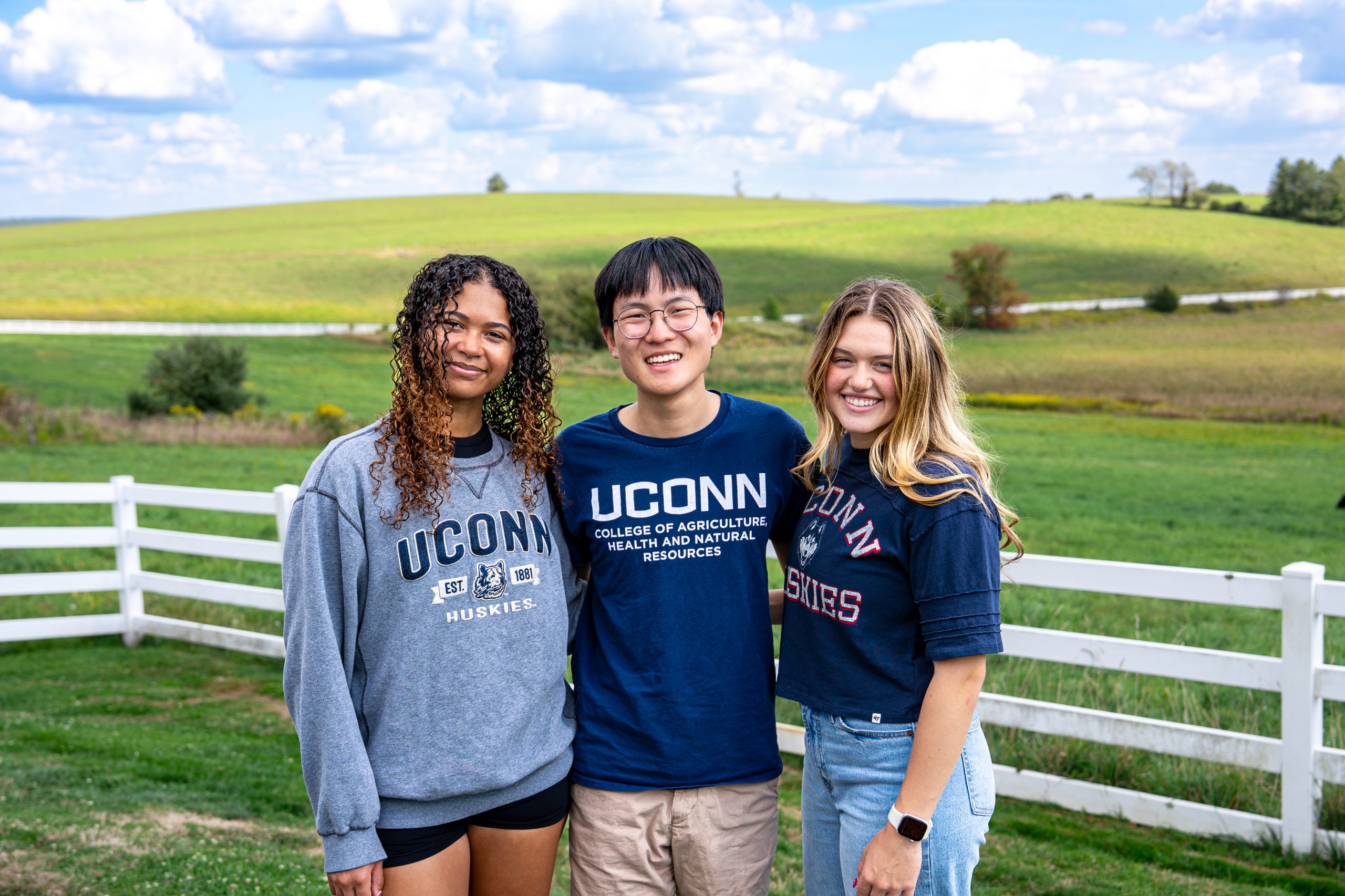 Three students posing in front of horsebarn hill
