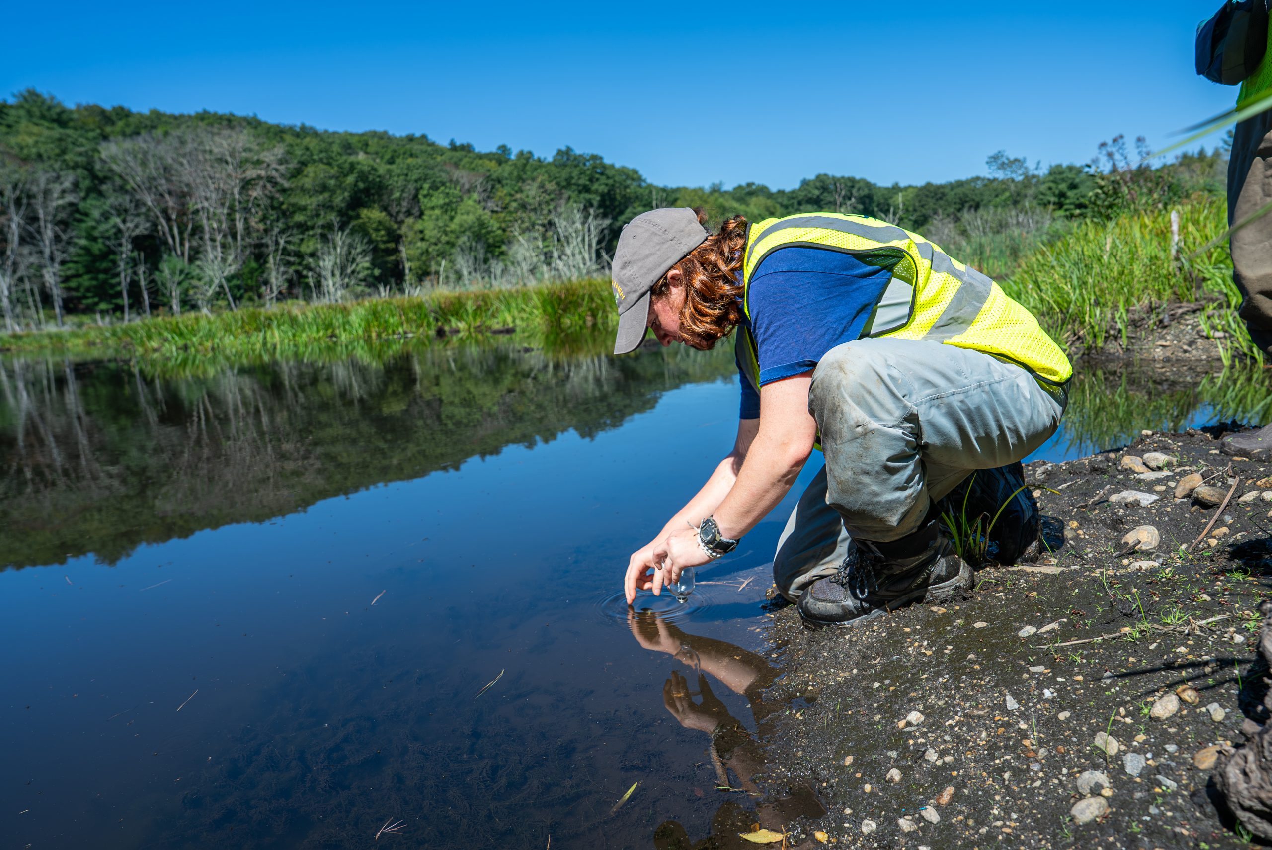 student researcher working at a river edge