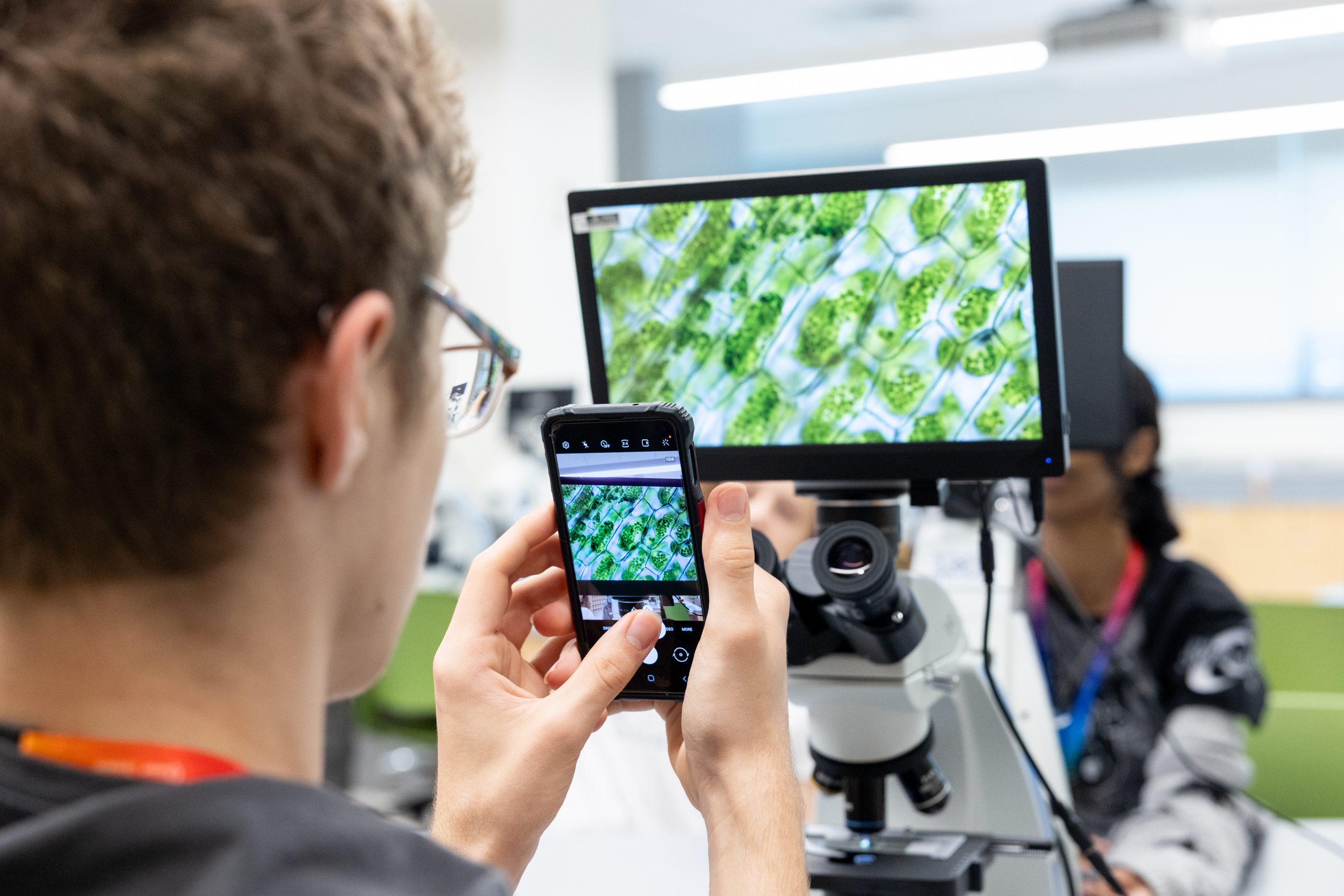 student taking a photo of microscope display